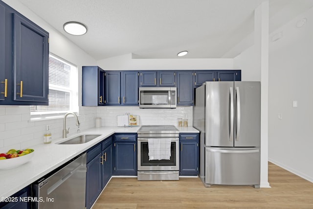 kitchen with blue cabinets, sink, tasteful backsplash, light hardwood / wood-style flooring, and appliances with stainless steel finishes