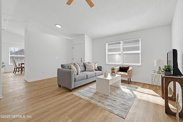 living room featuring ceiling fan, a textured ceiling, and light hardwood / wood-style floors