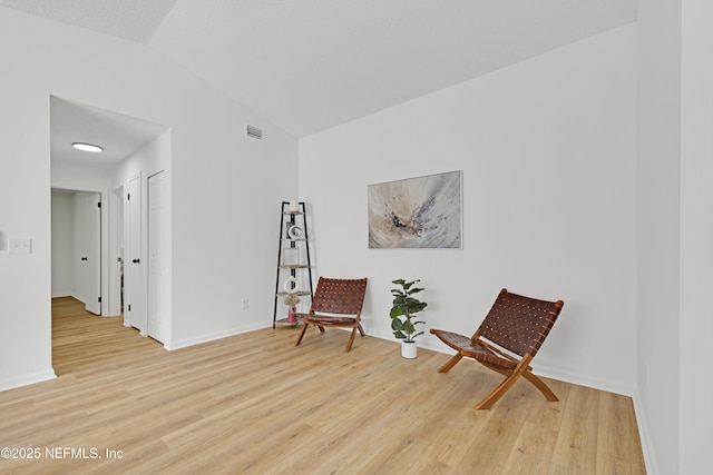 living area with vaulted ceiling and light wood-type flooring