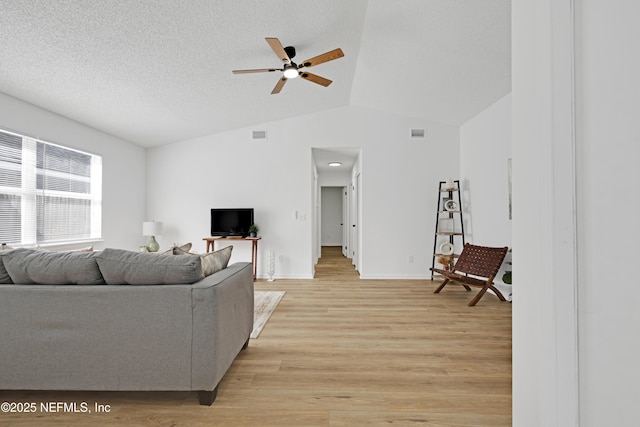 living room with lofted ceiling, ceiling fan, a textured ceiling, and light wood-type flooring