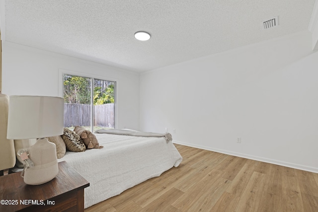 bedroom with a textured ceiling and light wood-type flooring