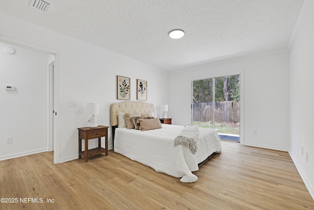 bedroom with hardwood / wood-style floors, access to exterior, and a textured ceiling