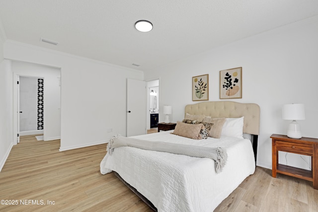 bedroom featuring crown molding, light hardwood / wood-style floors, and a textured ceiling