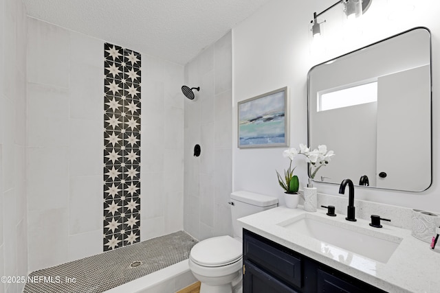 bathroom with vanity, a tile shower, a textured ceiling, and toilet