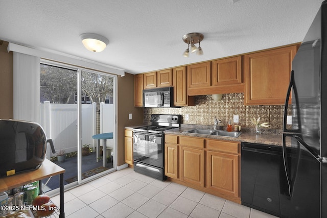 kitchen with light tile patterned flooring, sink, decorative backsplash, black appliances, and a textured ceiling