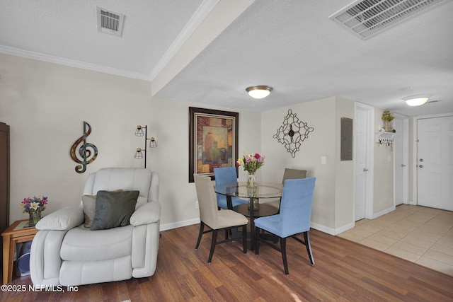 dining room featuring crown molding, hardwood / wood-style floors, electric panel, and a textured ceiling