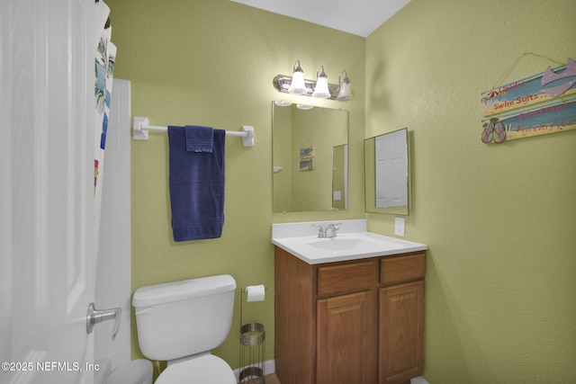 bathroom featuring vanity, walk in shower, and toilet