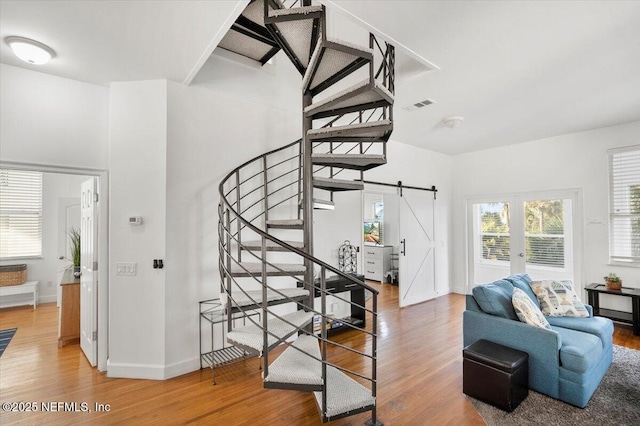 staircase with hardwood / wood-style floors, a barn door, and french doors