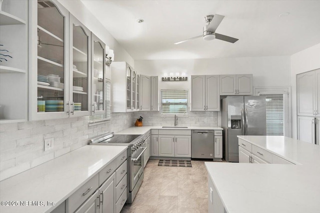 kitchen featuring sink, gray cabinetry, tasteful backsplash, ceiling fan, and stainless steel appliances