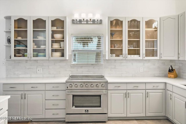 kitchen featuring high end range, decorative backsplash, and gray cabinetry