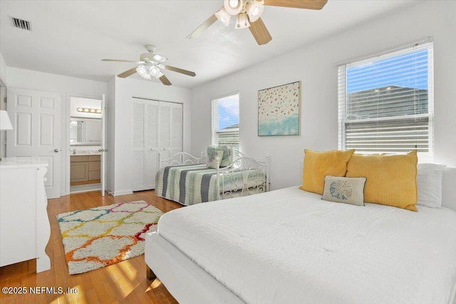 bedroom with ceiling fan, ensuite bath, light hardwood / wood-style floors, and a closet