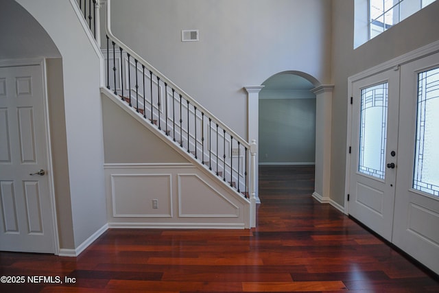 entryway with dark wood-type flooring, a towering ceiling, decorative columns, and french doors