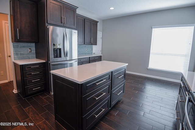 kitchen featuring decorative backsplash, dark brown cabinetry, stainless steel fridge with ice dispenser, and a kitchen island