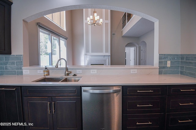 kitchen featuring pendant lighting, sink, dishwasher, light stone counters, and decorative backsplash