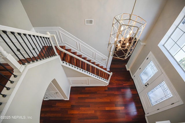 stairway featuring an inviting chandelier, hardwood / wood-style flooring, and a high ceiling