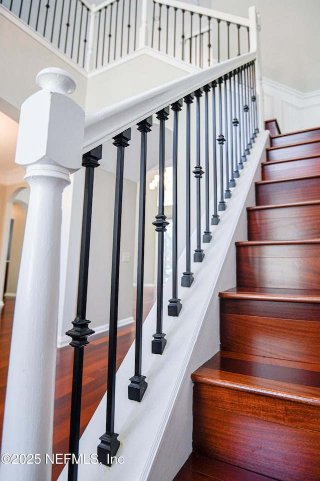 stairs with decorative columns and wood-type flooring