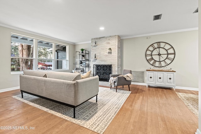 living room featuring crown molding, hardwood / wood-style flooring, and a fireplace