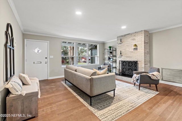 living room with ornamental molding, a brick fireplace, and light hardwood / wood-style floors