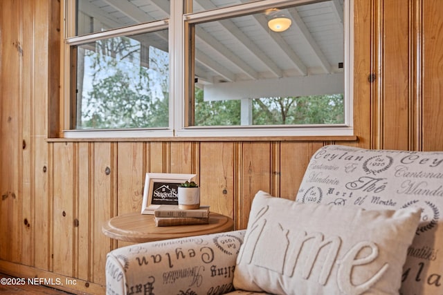 sitting room with vaulted ceiling with beams and wooden walls