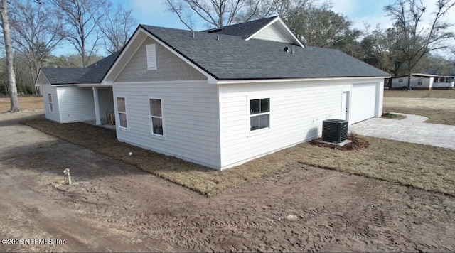 view of home's exterior featuring central air condition unit, driveway, and a shingled roof