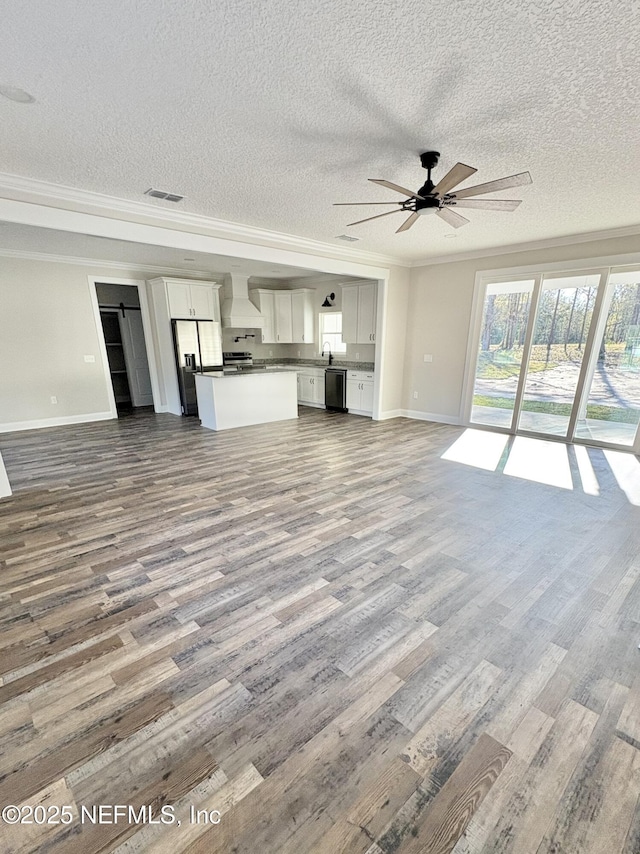 unfurnished living room featuring visible vents, ornamental molding, a ceiling fan, dark wood finished floors, and baseboards