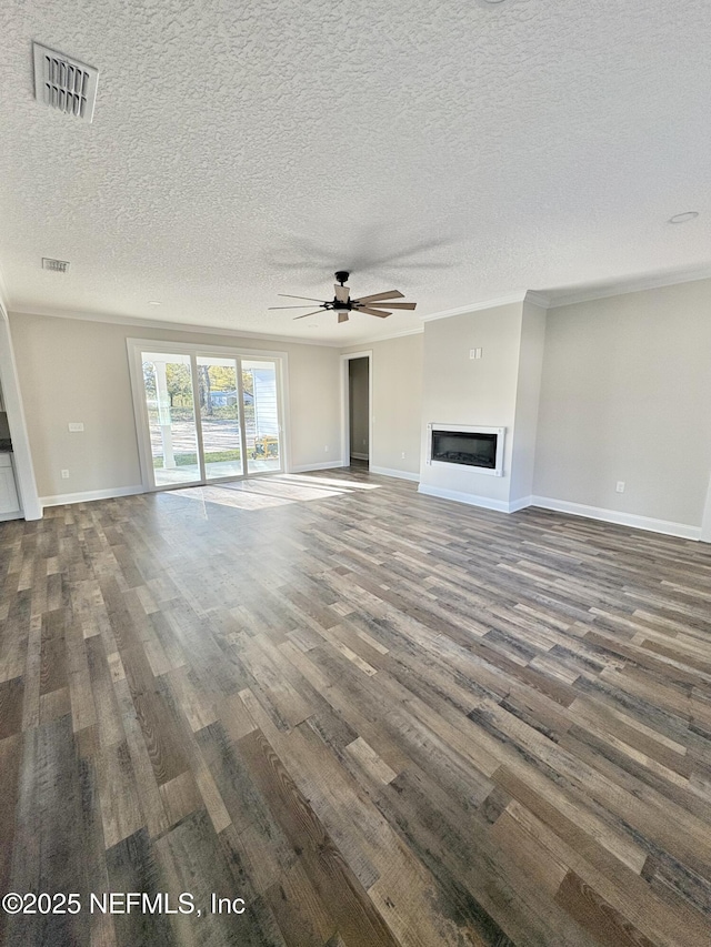 unfurnished living room with a glass covered fireplace, baseboards, visible vents, and dark wood-style flooring