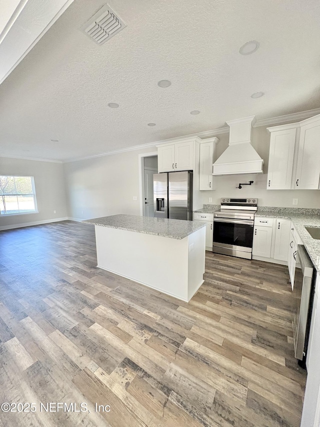 kitchen with visible vents, stainless steel appliances, light wood-style floors, crown molding, and custom exhaust hood