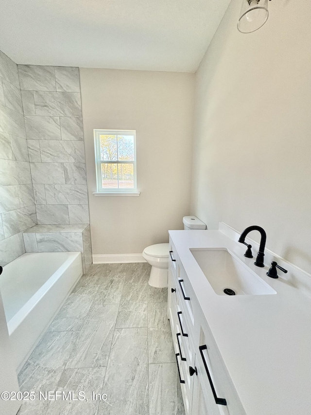 full bathroom with toilet, vanity, and baseboards