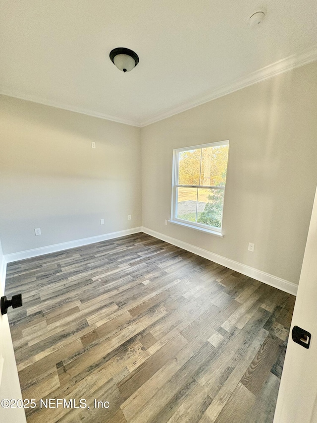 empty room featuring baseboards, dark wood-style flooring, and ornamental molding