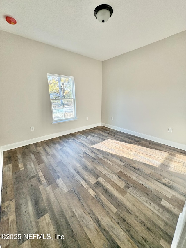 empty room featuring dark wood-type flooring and baseboards