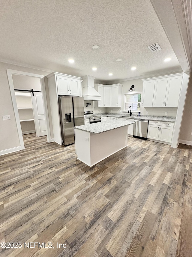6141 Charlie Rowe Dr, Macclenny, FL 32063 - kitchen with stainless steel appliances, premium range hood, a barn door, a sink, and light wood-style floors