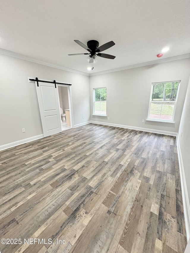 6141 Charlie Rowe Dr, Macclenny, FL 32063 - spare room with crown molding, a barn door, wood finished floors, and a ceiling fan