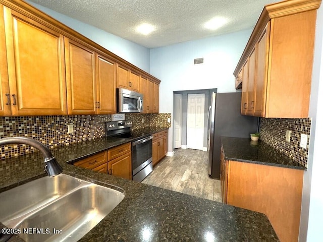 kitchen with stainless steel appliances, sink, a textured ceiling, and decorative backsplash