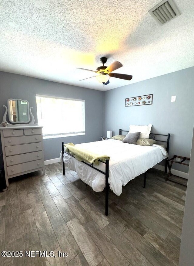 bedroom featuring dark hardwood / wood-style flooring, a textured ceiling, and ceiling fan