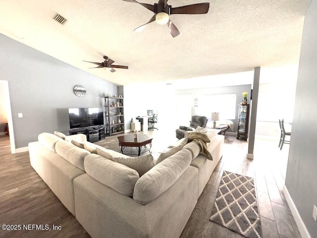 living room with vaulted ceiling, ceiling fan, hardwood / wood-style floors, and a textured ceiling