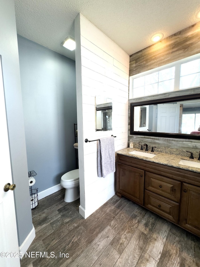 bathroom featuring wood-type flooring, toilet, a textured ceiling, and vanity