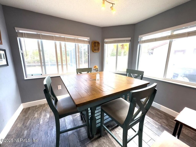 dining space featuring dark wood-type flooring and a textured ceiling