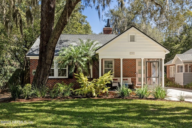 bungalow-style house featuring a porch, brick siding, roof with shingles, a front lawn, and a chimney