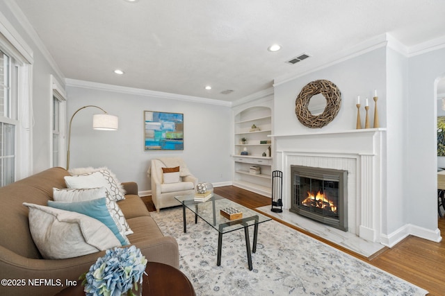 living room with a brick fireplace, baseboards, visible vents, and wood finished floors