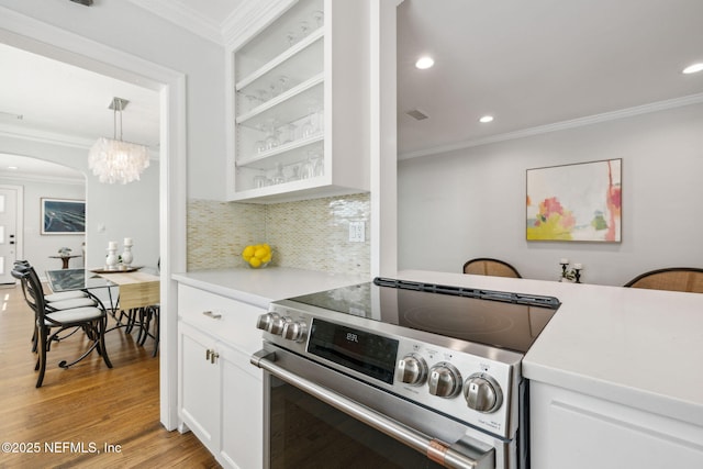 kitchen with light wood finished floors, crown molding, white cabinetry, and electric stove