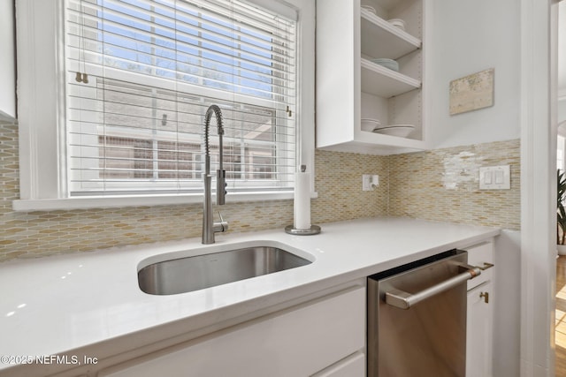 kitchen featuring open shelves, light countertops, white cabinetry, a sink, and dishwasher