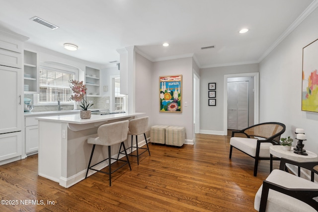 kitchen featuring visible vents, a kitchen breakfast bar, and wood finished floors