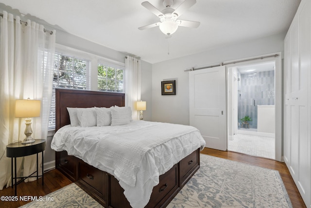 bedroom with dark wood-type flooring, ceiling fan, and a barn door