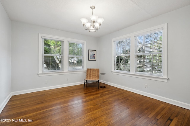 unfurnished room featuring a notable chandelier, baseboards, and wood finished floors