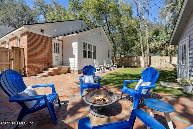 rear view of house featuring a fire pit, a lawn, fence, a patio area, and brick siding