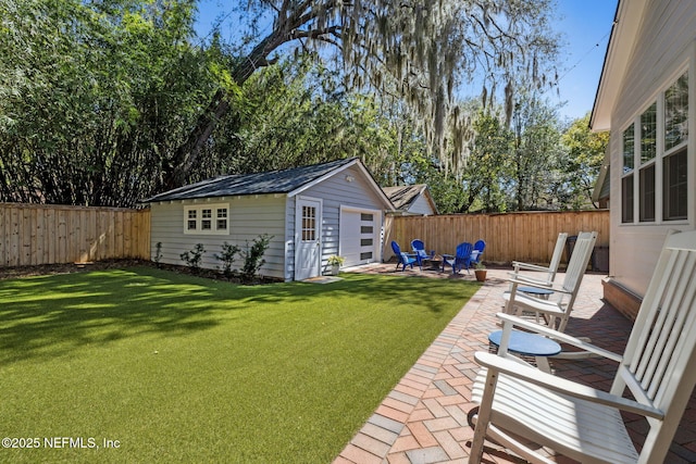 view of yard with an outbuilding, a fenced backyard, and a patio