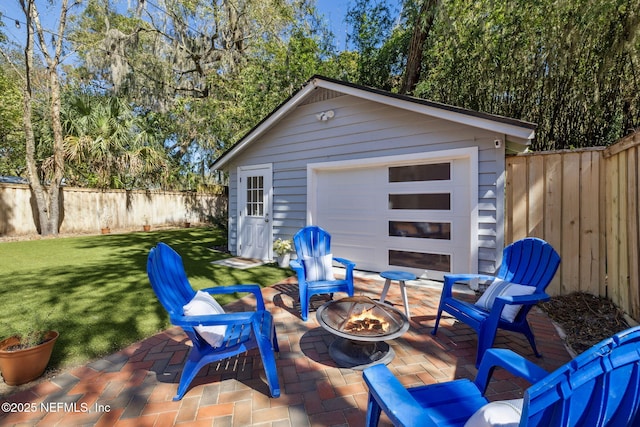 view of patio featuring a fire pit, an outdoor structure, and a fenced backyard