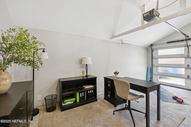 office space with a garage, concrete floors, and vaulted ceiling