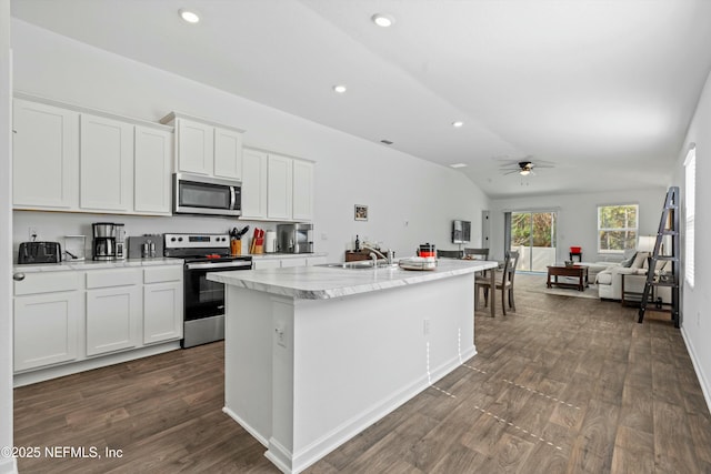 kitchen with appliances with stainless steel finishes, sink, white cabinets, dark wood-type flooring, and a center island with sink