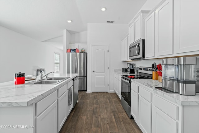 kitchen featuring appliances with stainless steel finishes, sink, white cabinets, dark hardwood / wood-style flooring, and a center island with sink